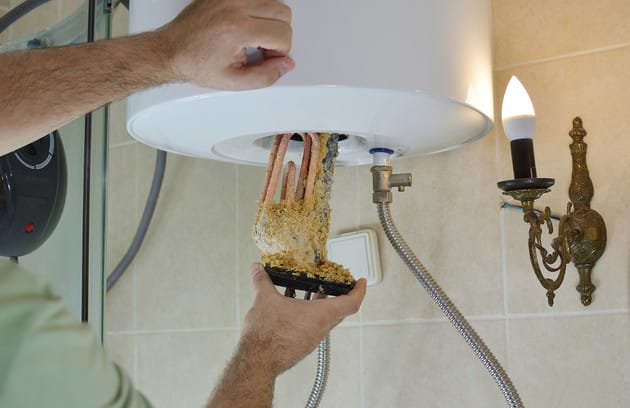 Technician removing mineral buildup from a water heater in Englewood
