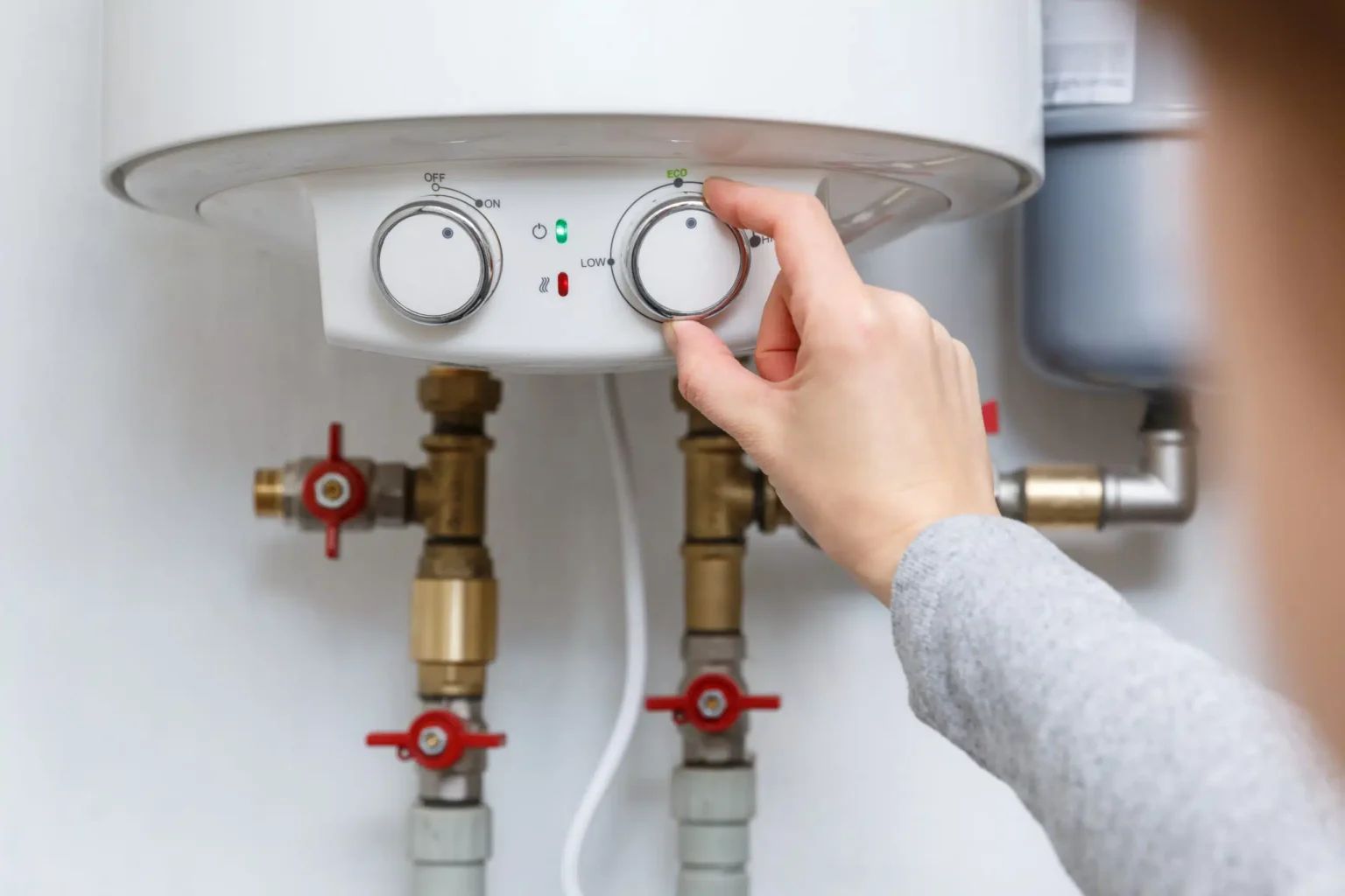 Homeowner adjusting the temperature controls on a water heater in Englewood